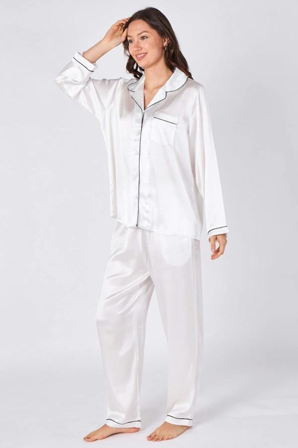 Woman wearing white satin pajamas on a plain background