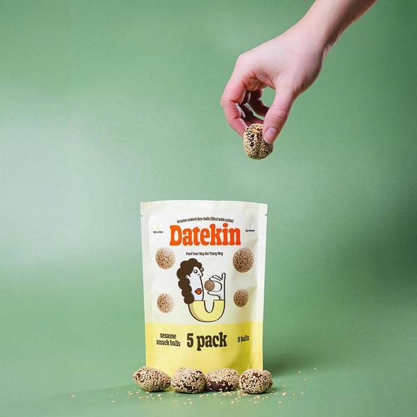 Datekin snack balls packaging with a hand holding a ball against a green background