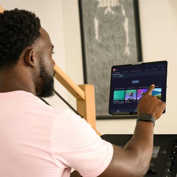 Person using a tablet with a music streaming app on a treadmill