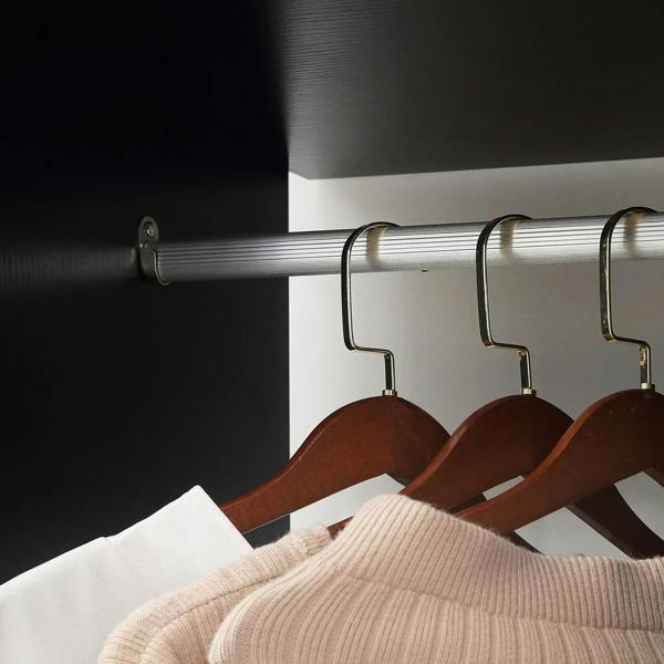 Black hanging rail with brown hangers holding folded knit garments