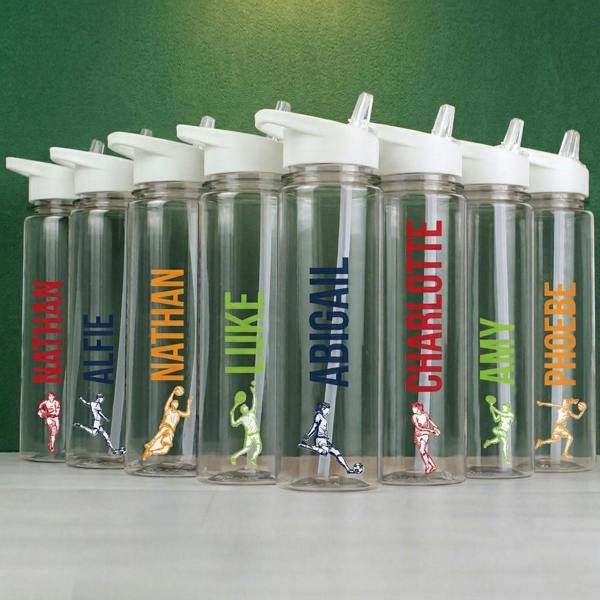 A line of transparent 750ml sports water bottles with colourful custom names and athlete illustrations standing in front of a textured dark green wall.