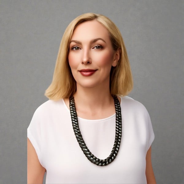Woman wearing a white top and a single chain black aluminium and metal chain necklace a against a plain background