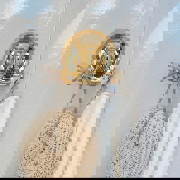 Polished brass double towel hook on bathroom wall