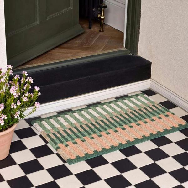 Doormat with geometric pattern on a checkered floor in front of a door.