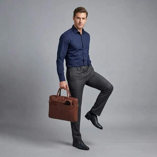 Man in formal attire holding a brown leather briefcase against a gray background