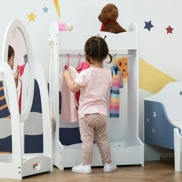 White kids clothing rack with hanging rail and bottom shelf, with toddler reaching for clothes