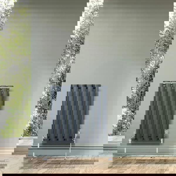 Oval single column radiator in anthracite grey, featuring a sleek design, mounted on a wall with a modern interior backdrop