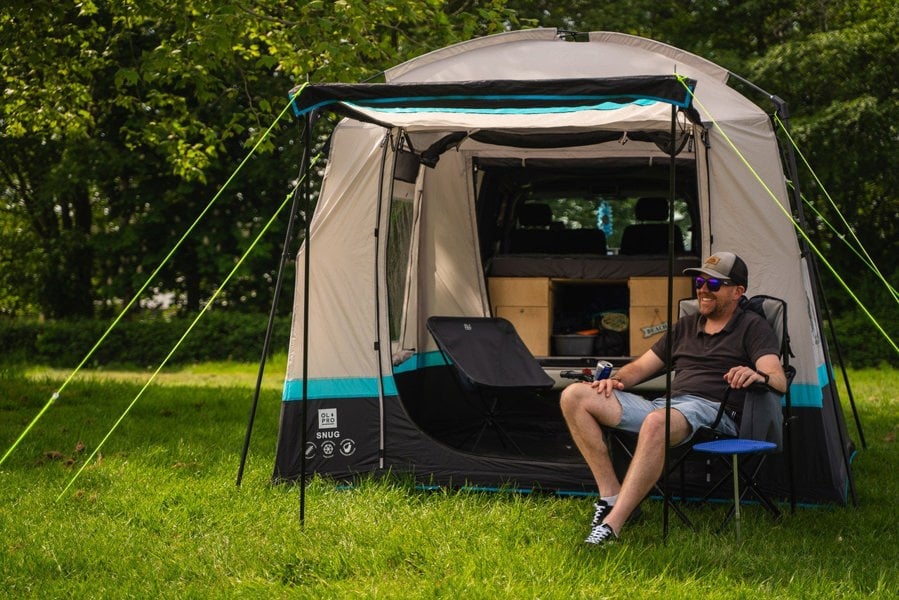 A man sits outside the Snug Poled Tailgate Awning by  OLPRO