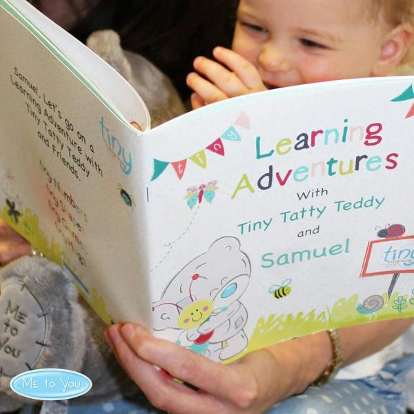 A child looking at an open personalised Tiny Tatty Teddy Learning Adventures book displaying the custom name Samuel on the front cover.
