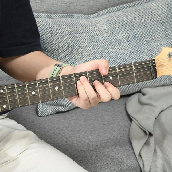 Electric guitar neck and strings with fretting hand on dark finish body
