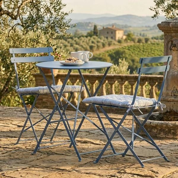 A powder-coated blue table and two chairs bistro set styled along a lavender-lined gravel garden path.