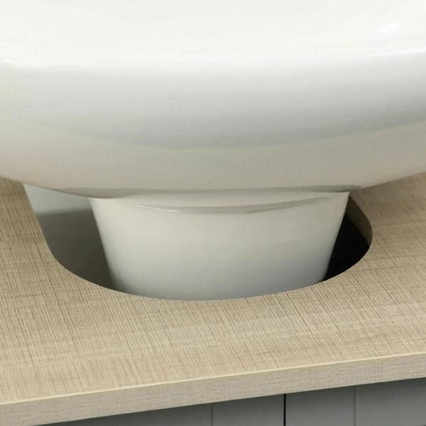White sink basin on light wood-look vanity top, viewed from close-up angle