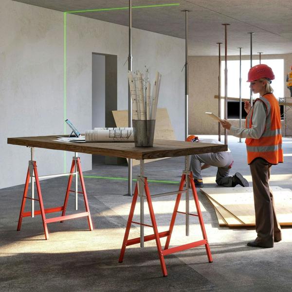 Adjustable red and gray sawhorses supporting a large wood board during construction work