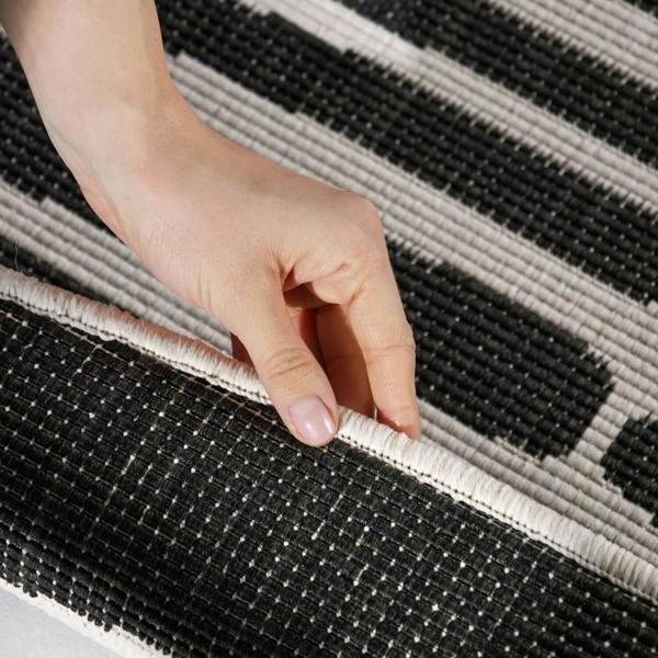 Hand touching a textured black and gray rug