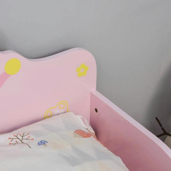 Pink toddler bed side panel with small floral decals and safety rail, with bedding