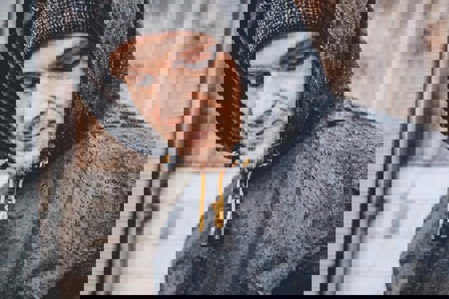 JCB Mens Two-Piece Rain Set Rainsuit Trousers and Jacket, waterproof rain suit displayed on a man wearing a hooded jacket with water droplets on the fabric.