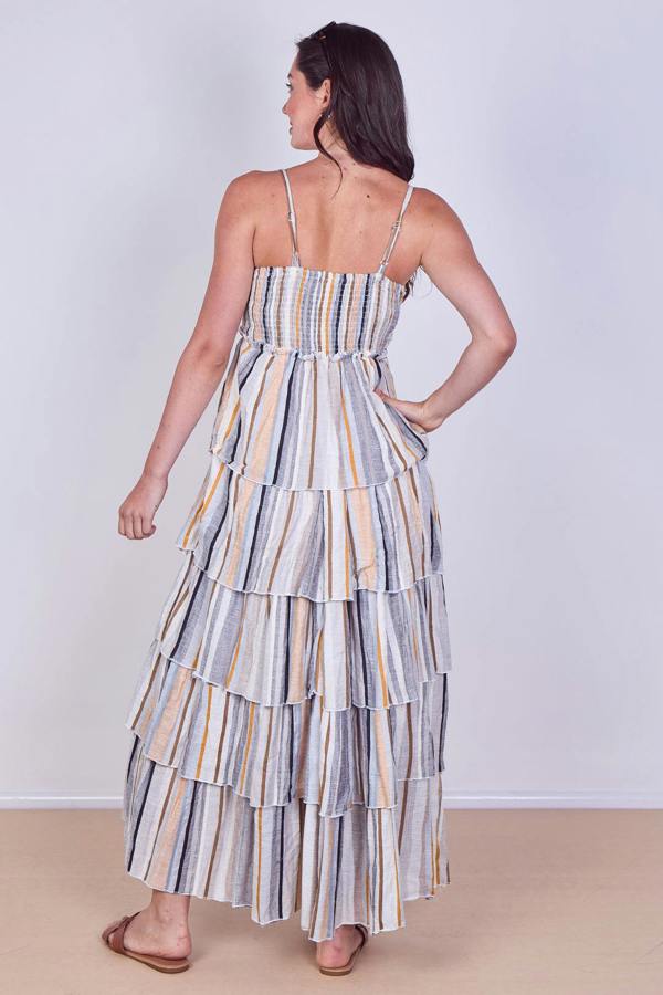 Woman wearing a striped tiered dress against a plain background