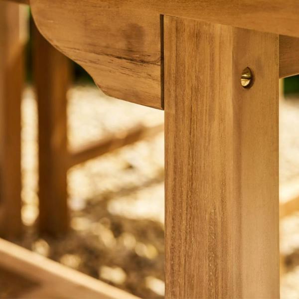 Close-up detail of the solid teak table leg and frame joinery featuring a flush brass screw fitting.