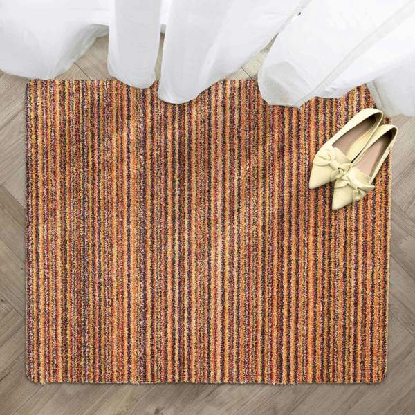 Striped doormat with a pair of shoes on a wooden floor