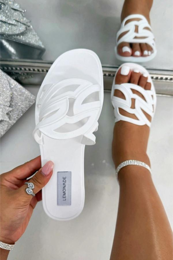 White sandals with 'Lemonade' branding held by a hand, worn on feet.