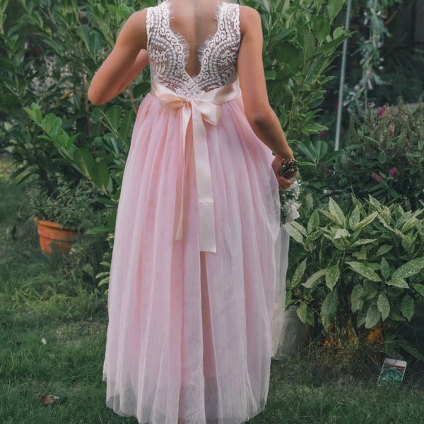 Person wearing a pink dress with a white bow in a garden setting