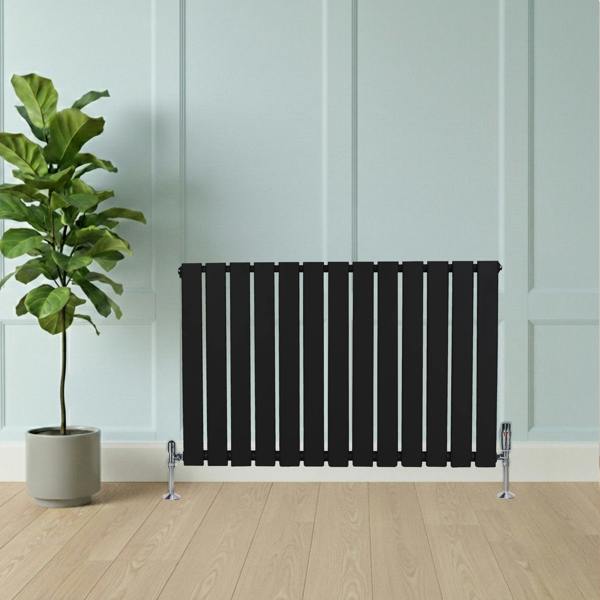 Flat black single column radiator, 600 x 910mm, with vertical slats, positioned next to a potted plant on a wooden floor
