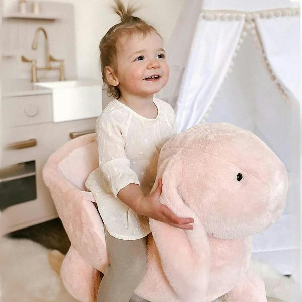 Pink plush rabbit rocking horse ride-on with child seated, facing forward