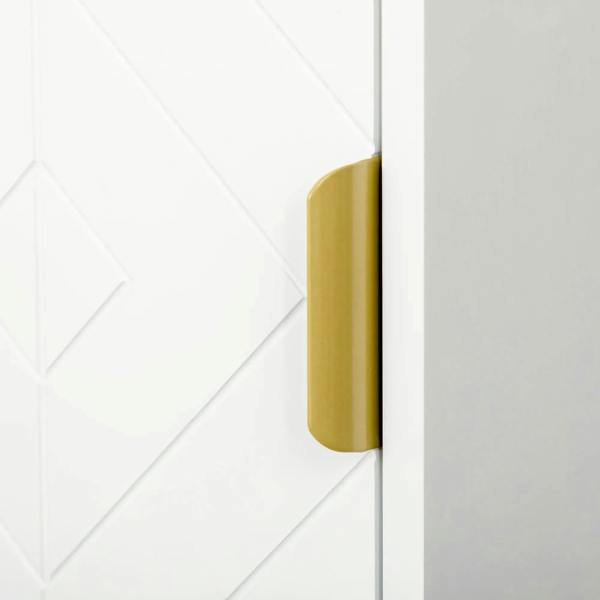 Gold door handle on white bathroom cabinet with textured geometric door panel