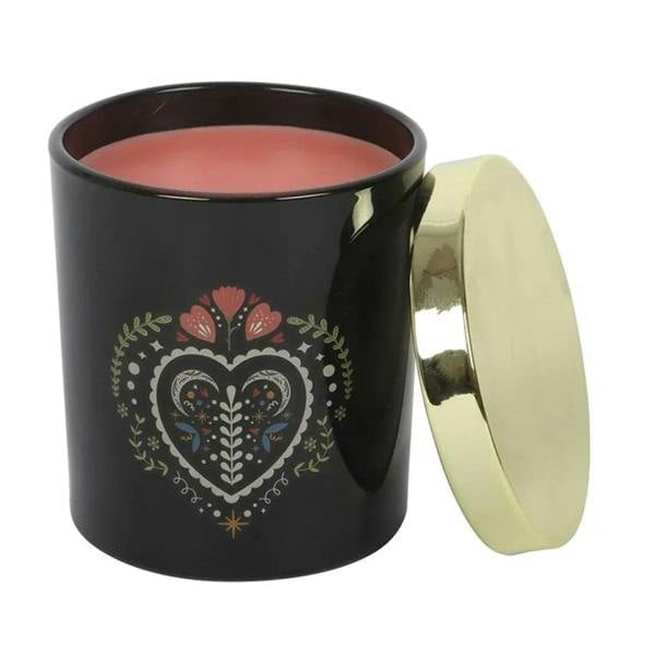 Black candle jar with gold lid open, showing pink wax and heart floral artwork