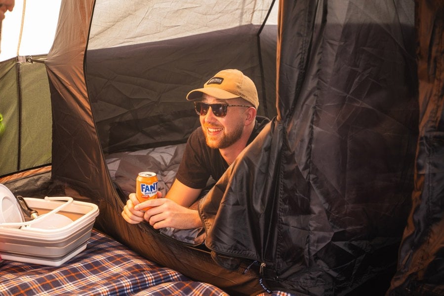 A man lies on an air mattress inside one of the darkened sleeping pods inside the Wichenford 8.0 tent