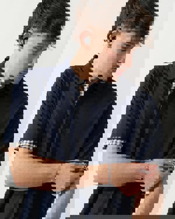 close up shot of a model wearing an Aquascutum Mens Club Check Stretch Piquet Sleeves Polo Shirt in Navy 11