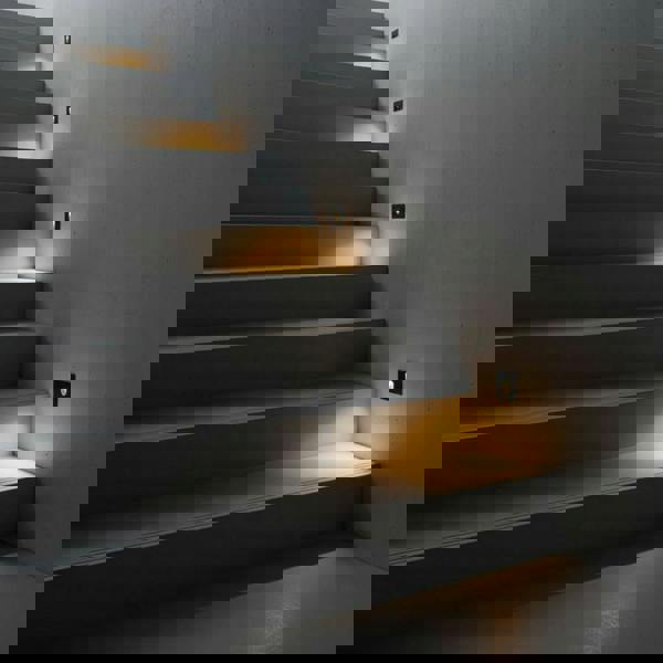 black outdoor step light fixture mounted on the wall alongside outside steps 