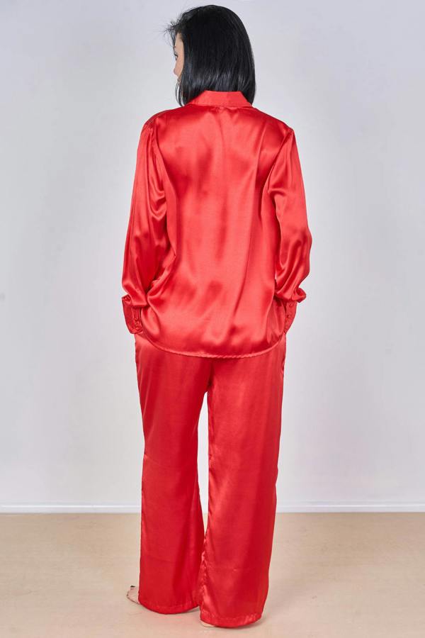 Person wearing a red satin pajama set against a white background