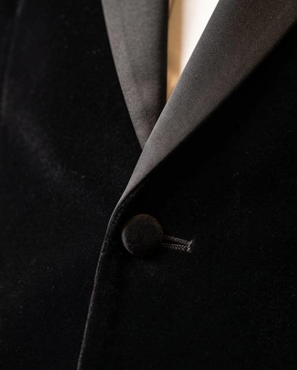 Close-up of a black coat with a button on a dark background