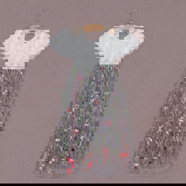 Children's dress with floral design on a hanger against a brown background