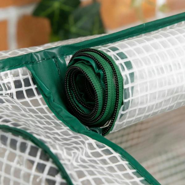 Rolled greenhouse PE cover edge with green tie strap and stitched seam on mesh fabric