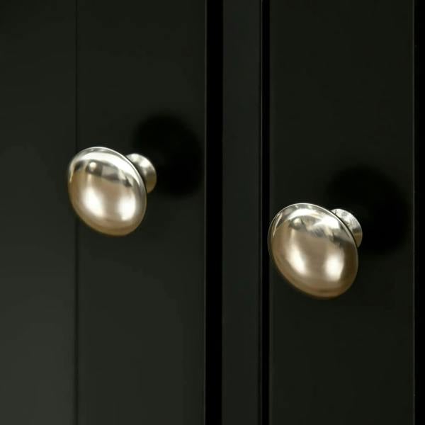 Close-up of shiny metal knob handles on black cabinet doors