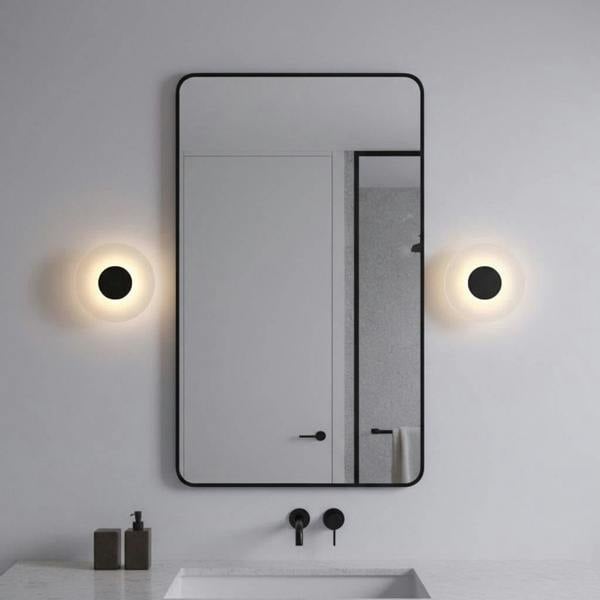 black bath sconce light mounted either side of a mirror in a bathroom 