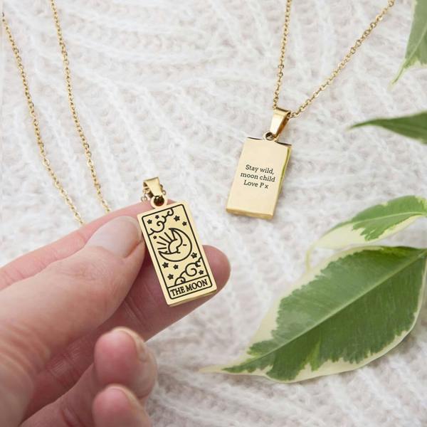 A luxurious gold plated rectangular moon tarot card pendant necklace resting inside a black Abode Home and Gifts presentation box.