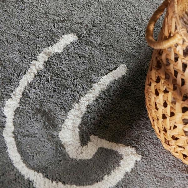 Gray rug with a white abstract design and a woven basket on a gray surface