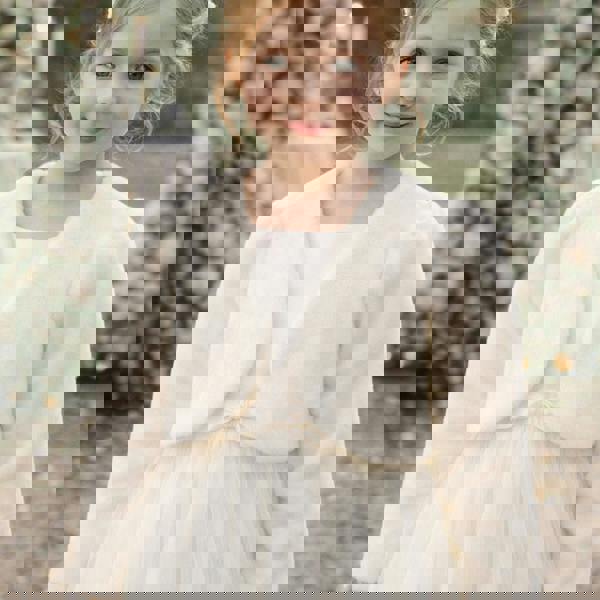 Young girl wearing a white dress with a matching shrug in a garden setting