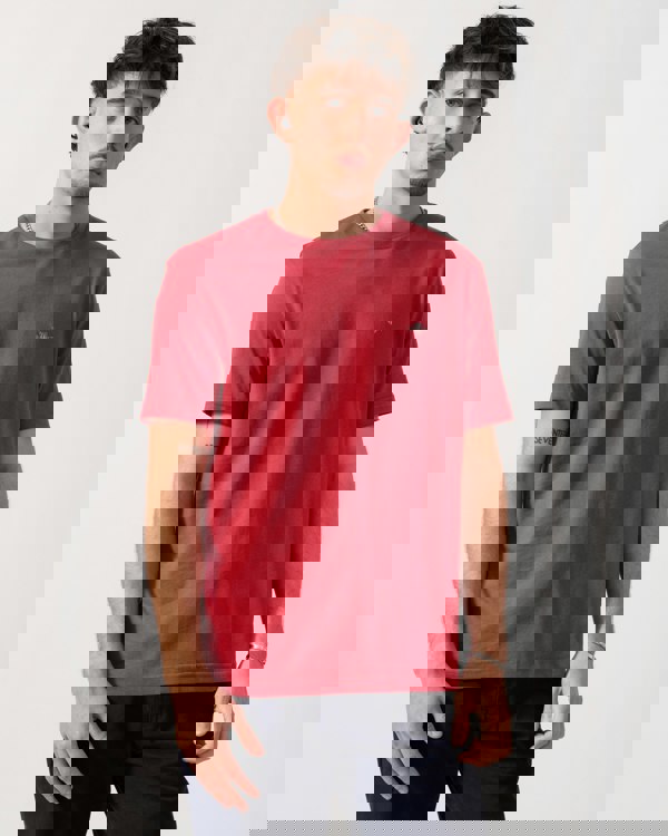 Man wearing a red t-shirt with a small logo on a white background