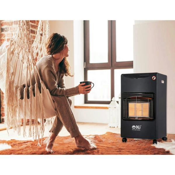 Woman holding a cup in front of a space heater in a room