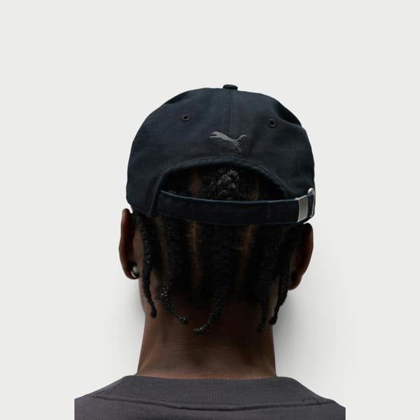 Supplied Fashion Puma black baseball cap with embroidered logo on back, worn by a person with braided hair