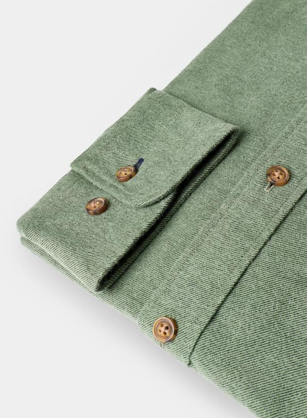 Folded green shirt with brown buttons on a white background