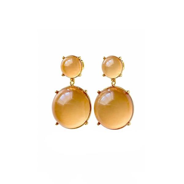 A pair of gold drop earrings featuring large, smooth oval amber-colored gemstones and smaller round studs above them, set against a plain white background.