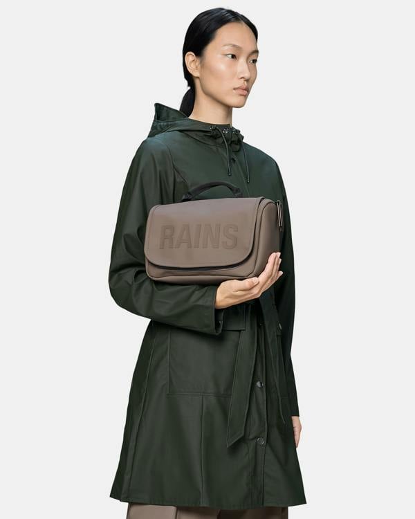 model holding a Rains Texel Wash Bag in 173 Cinder