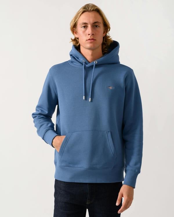 model wearing a GANT Mens Regular Fit Shield Logo Pullover Hoodie in 476 Blue Horizon