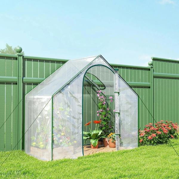 Clear mini greenhouse with steel frame in garden, front zippered door and visible plants inside