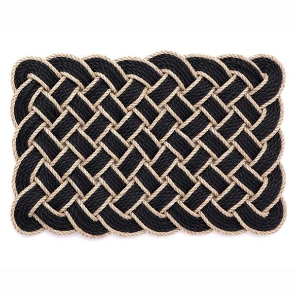 Nautical-style woven mat with black and beige rope on a white background